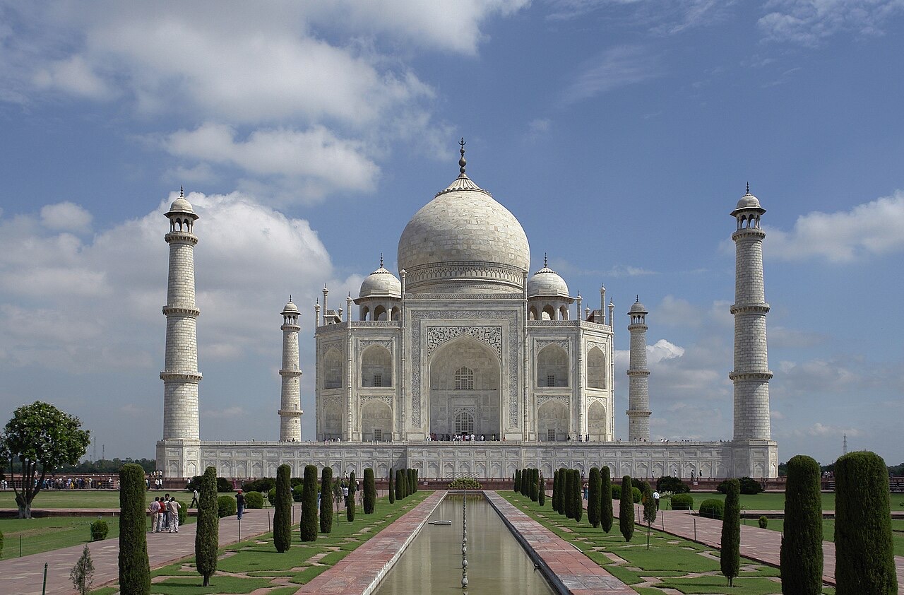 The white marble Taj Mahal with its four minarets under a blue sky
