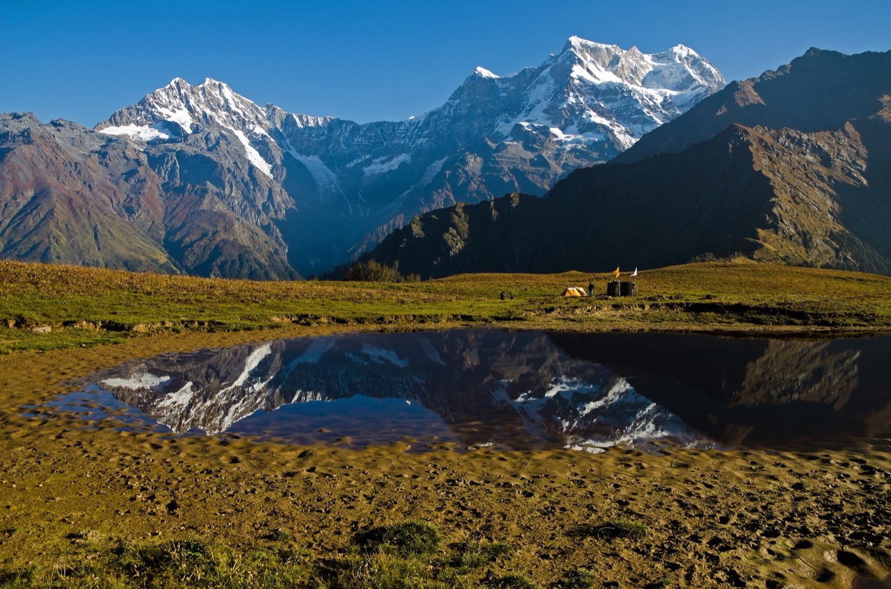 Snow peaks of the Chaukhamba massif reflected in a still Himalayan lake in Uttarakhand